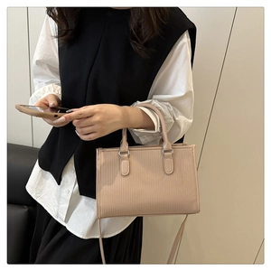 Detail of light beige pleated pillow bag with vertical stripes and cylindrical handles
