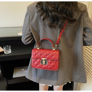 Rear view of a red quilted crossbody bag with gold buckle on a grey blazer outfit