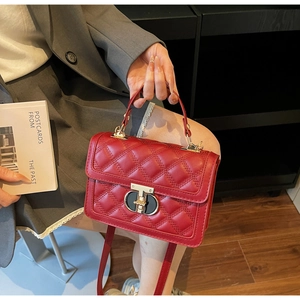 Detail of red quilted leather handbag with gold twist-lock and adjustable shoulder strap