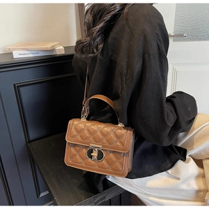 Brown quilted crossbody bag with gold twist lock and adjustable strap in lifestyle setting
