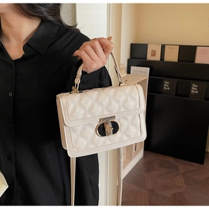 Detail of white quilted leather texture and gold twist lock on stylish handbag