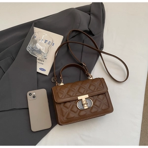 Close-up of brown quilted handbag with golden lock on a grey suit jacket background