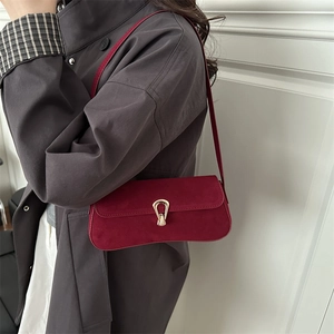 Burgundy suede baguette shoulder bag with gold horseshoe clasp shown on a model