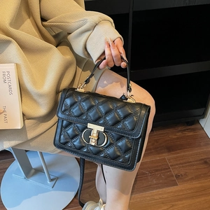Quilted black PU leather crossbody bag with gold T-lock and top handle held by a model