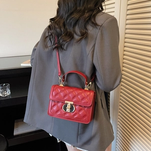 Quilted red shoulder bag with gold clasp and top handle worn with a grey blazer