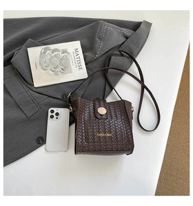 Detailed view of dark brown woven leather bucket bag with gold magnetic buckle and shoulder strap