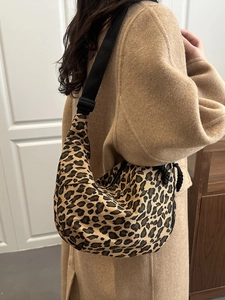 Detail of hobo bag featuring leopard print fabric and adjustable black strap