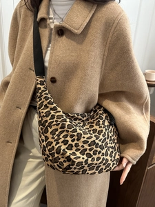 Detail of trendy leopard print crescent bag with black nylon strap and stylish autumn outfit