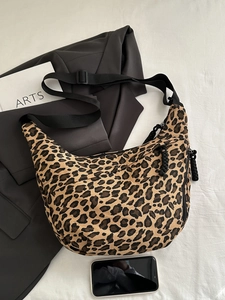 Close-up of leopard print crossbody bag with adjustable strap and zip detail on canvas