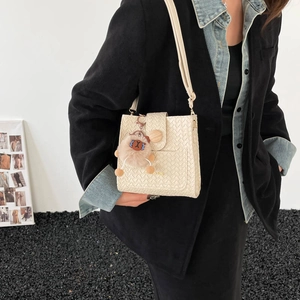 Minimalist beige woven crossbody bag with round buckle and cute plush pendant