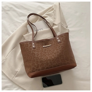 Close-up of leopard print tote bag with gold FASHION label and leather trim detailing