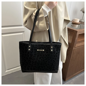 Close-up of black leopard print suede tote with elegant gold metal fashion plaque