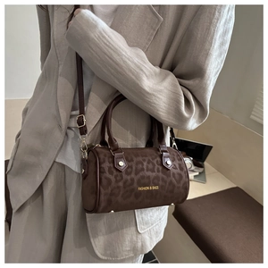 Detail of leopard print cylinder bag featuring double handles and a detachable strap