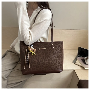 Close-up of leopard print tote bag with metal Fashion logo and cute bear charm