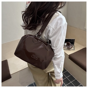 Dettaglio della borsa a tracolla in pelle lucida marrone scuro con anello e logo del brand