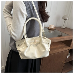 Vue détaillée du sac seau plissé beige avec détails dorés et bandoulière élégante
