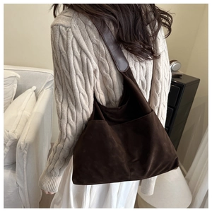 Detailed view of brown suede hobo bag featuring wide straps and two front pockets