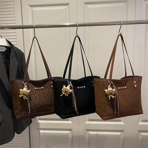 Large leopard print tote bags in brown and black with bear charms on display