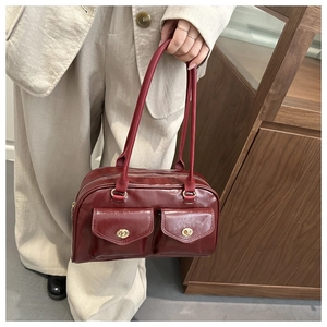 Detail of dark red vintage faux leather handbag with golden metal twist-lock front pockets