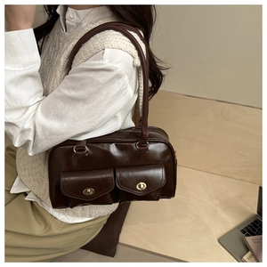 Detail of a dark brown glossy leather Boston bag with dual gold twist-lock front pockets