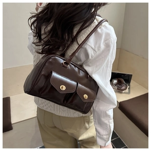 Close-up of deep brown glossy PU leather underarm bag with gold buckles and dual front pockets