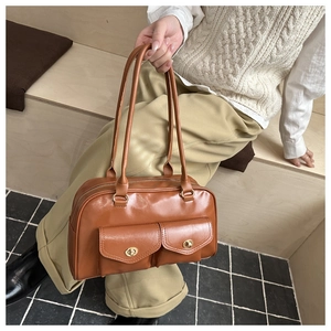 Detailed view of brown leather shoulder bag featuring two front pockets and golden turn locks