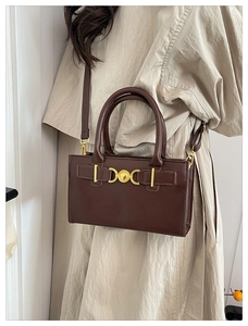 Dettaglio di una borsa a tracolla in pelle marrone scuro con chiusura a cuore dorata