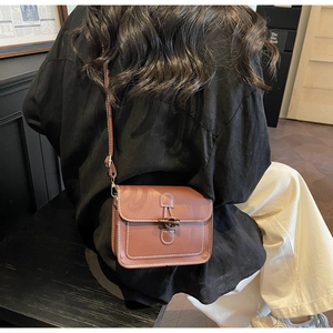 Close-up of brown vintage leather square bag with horn buckle and white stitching details