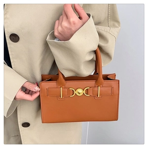 Detailed shot of brown leather handbag featuring a unique gold heart-shaped metal buckle