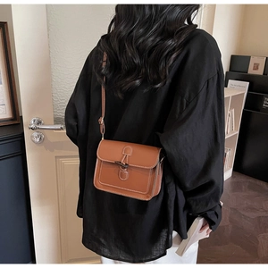 Detail of caramel vintage messenger bag with toggle closure and contrast stitching