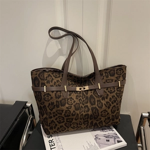 Leopard print tote bag met bruine lederen riemen en metalen draaisluiting op stoel