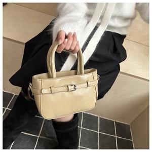 Detail of a beige mini handbag with buckle decor and dual handles on wooden stairs