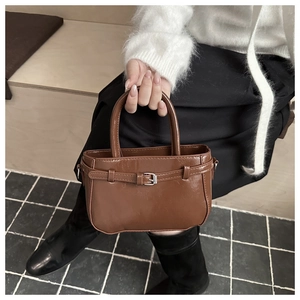 Detail of dark brown vintage faux leather handbag with silver buckle and top handles