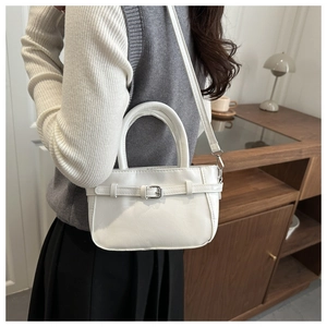 Detail of white leather small crossbody bag with buckle strap on a lifestyle background
