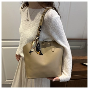 Chic beige leather bucket bag featuring a decorative silk scarf on the handle