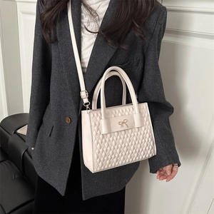 Chic beige quilted square handbag with gold bow and adjustable crossbody strap