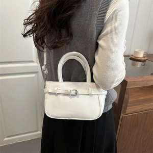 Chic white PU leather handbag with decorative belt buckle shown in a lifestyle setting