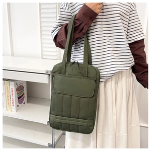 Army green quilted laptop tote bag with front pocket shown in a lifestyle model shot