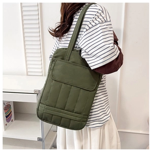 Detailed view of dark green quilted tote bag with front pocket flap on shoulder