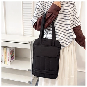 Close-up of minimalist black tote bag with quilted texture and large front flap pocket