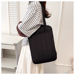 Close-up of black tote bag with vertical quilted texture and double shoulder straps