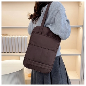 Detail view of coffee brown nylon tote bag with large flap pocket worn on shoulder