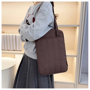 Detailed view of vertical quilted stitching on dark brown chic tote bag worn by a model