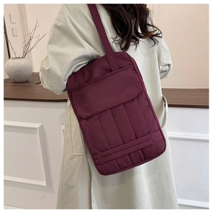 Vertical burgundy quilted tote bag with front flap pocket shown on model's shoulder