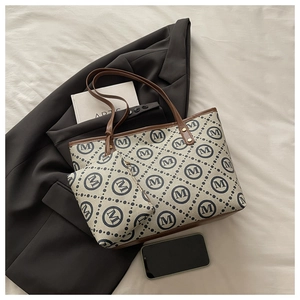 Detail of beige canvas tote bag and matching pouch with blue M-logo and brown leather trim