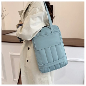 Detail of light blue quilted tote bag fabric with vertical stripes and front pocket