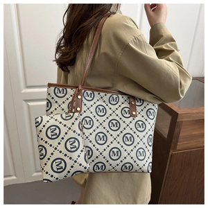 Detail view of large printed tote bag set with brown leather straps worn by a model