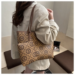 Detailed view of the brown monogram tote bag set shown on a shoulder in a natural setting