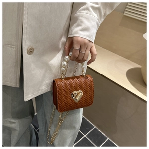 Close-up of woven brown handbag featuring a golden heart lock and elegant pearl handle