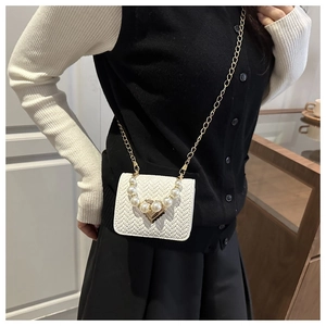 Detail of woven beige leather mini bag with gold heart clasp and large pearl strap handle